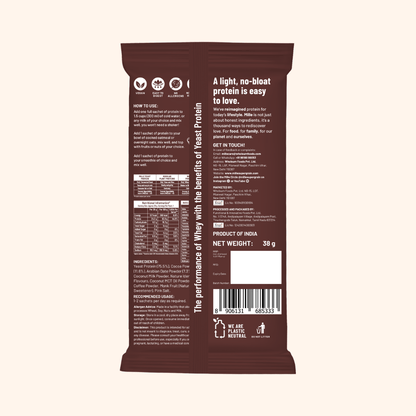 The back of a dark brown protein powder pouch, showing product details, ingredients, nutritional information, and a barcode, set against a solid light beige background.
